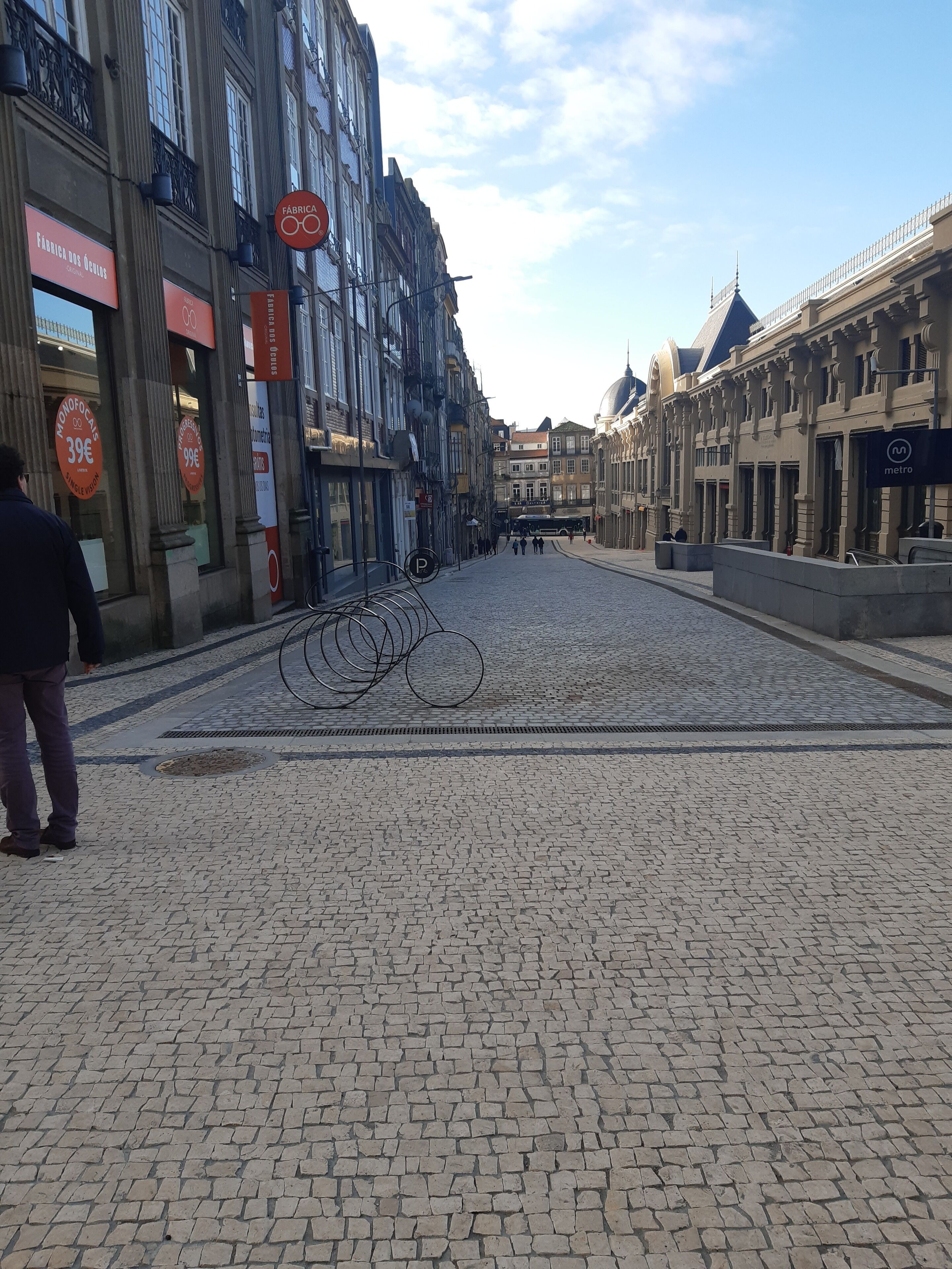 A cobblestone street lined with historic buildings, a metro sign, and a person walking.