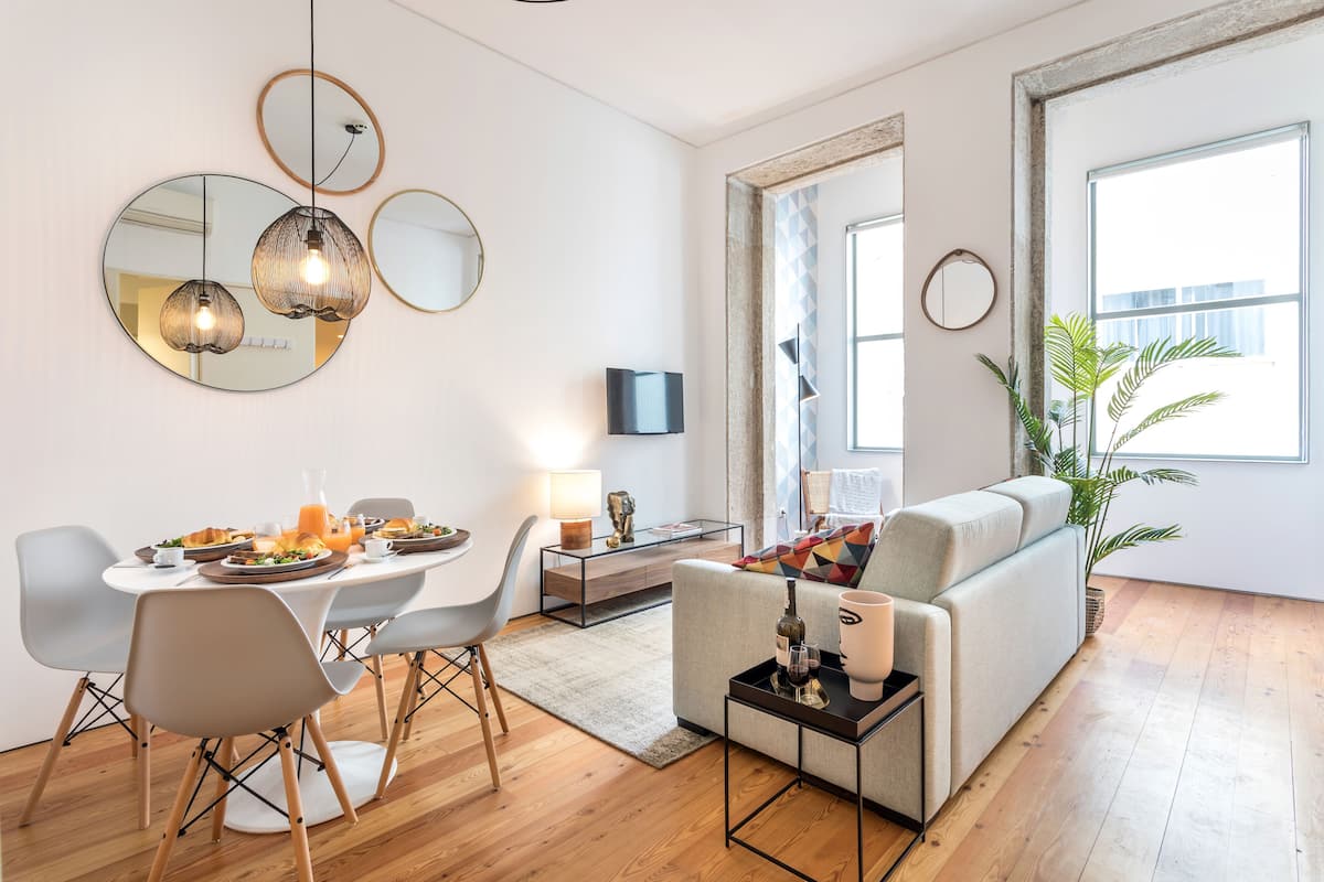 A modern living room with a dining area, featuring a sofa, chairs, a coffee table, and a dining table set for a meal.