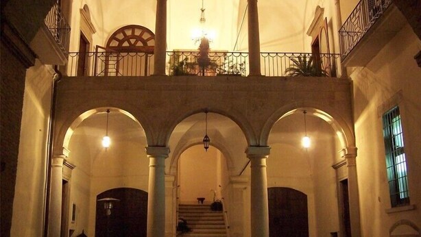 A building with a central courtyard, multiple arches, and a staircase leading to an upper level. - B&B Casa Cavalli (Lucera)
