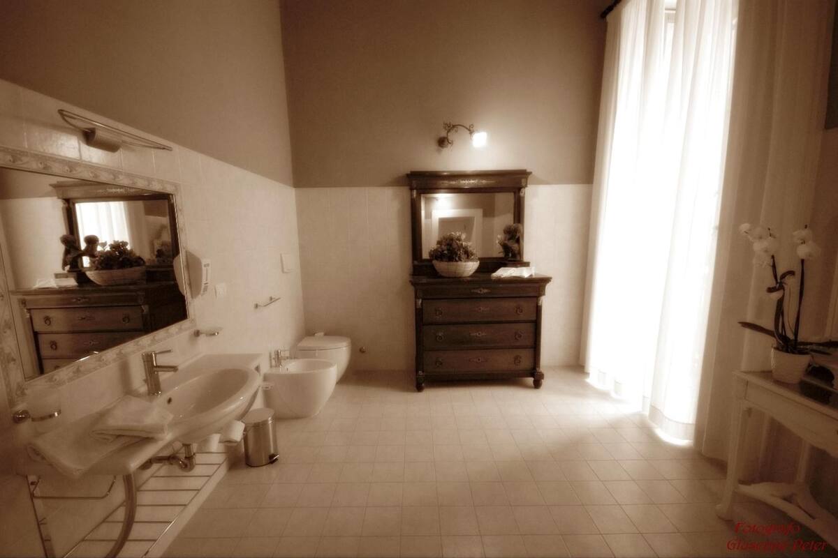A bathroom with a large mirror, a sink, a bathtub, a toilet, and a vanity with drawers.