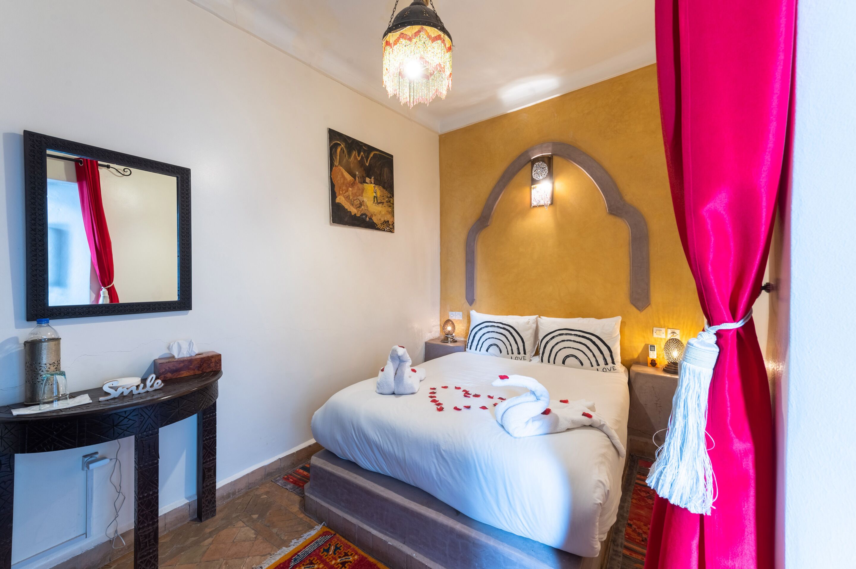 Habitación de hotel con cama, mesita de noche, espejo y una obra de arte colgada en la pared.