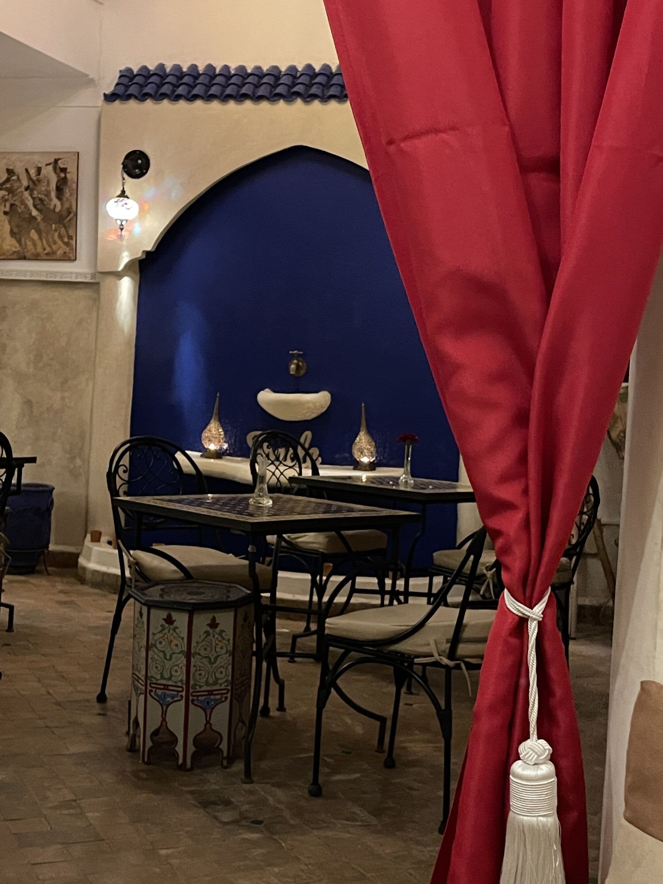 A dining area with a blue wall, a table with chairs, and a red curtain.