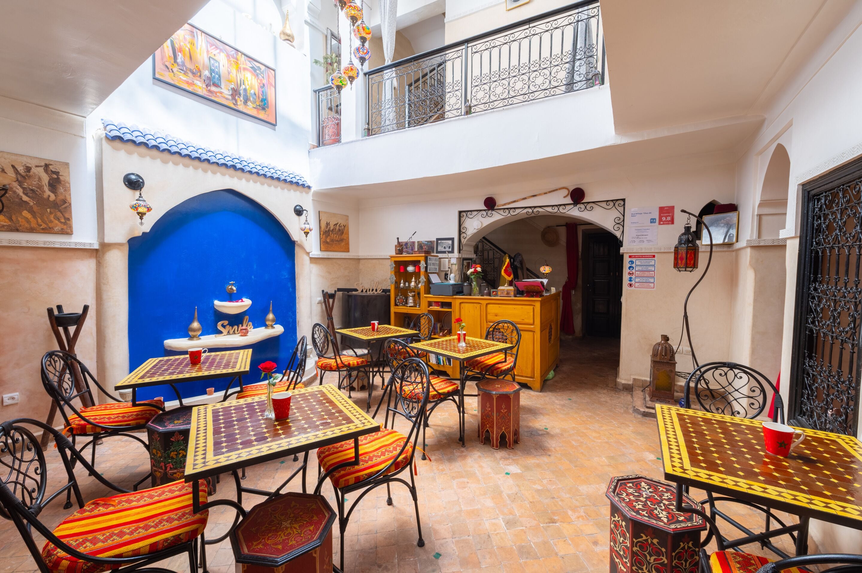 Un patio con mobiliario exterior, un arco azul y un balcón con barandas decorativas.
