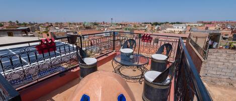 A rooftop terrace with a table and chairs, a red sofa, and a view of the cityscape.