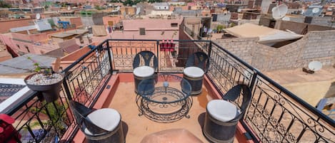 Una terraza en la azotea con una mesa redonda, cuatro sillas y una planta en maceta.