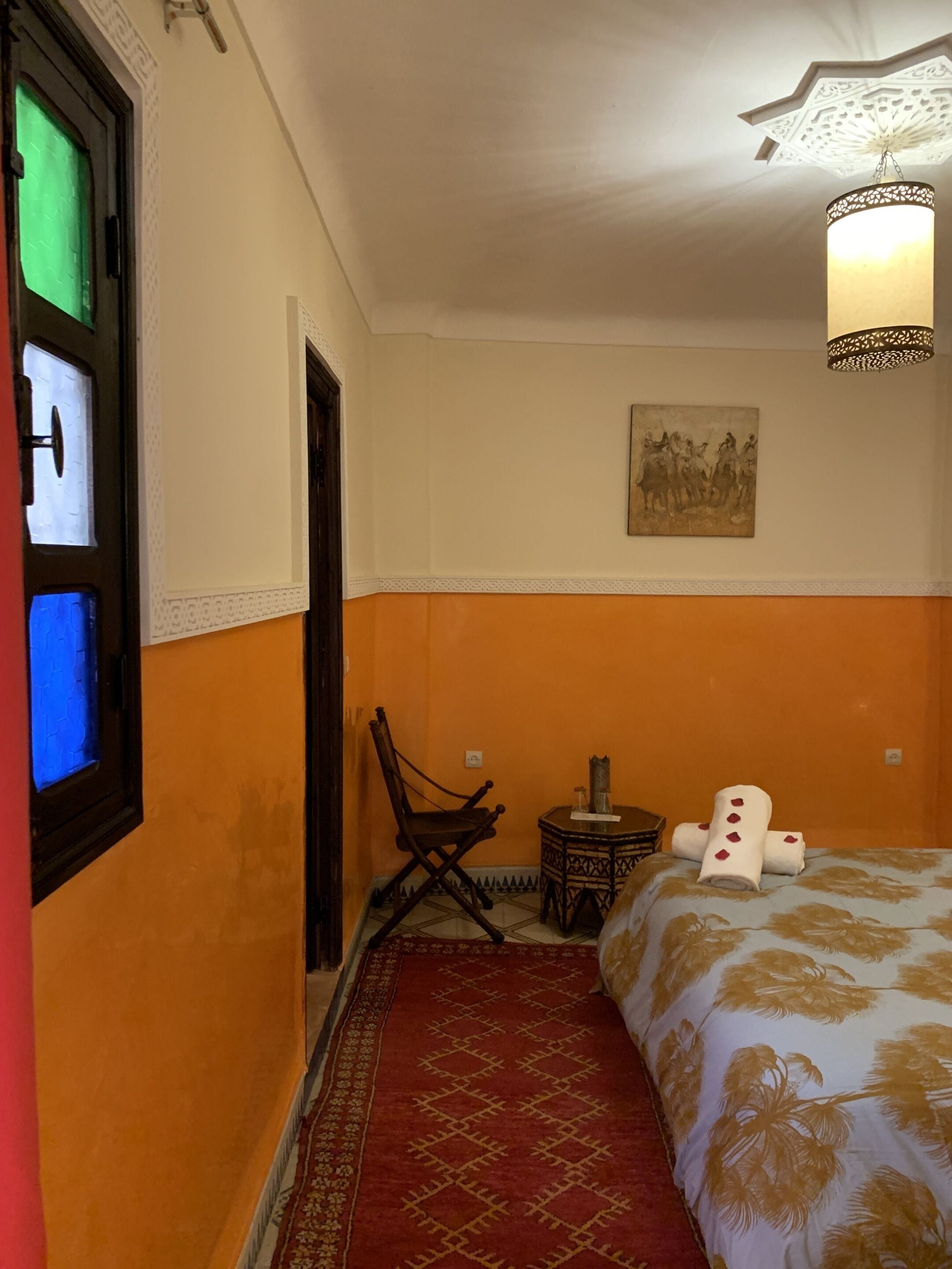 A room with a bed, a chair, a small table, and a wall-mounted painting.