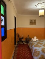 A room with a bed, a chair, a small table, and a wall-mounted painting.