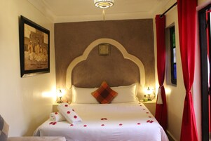 Una camera d'albergo con un letto, un quadro appeso al muro e una tenda rossa.