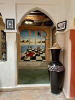 Una habitación con piso a cuadros, un jarrón grande y cuadros en las paredes.