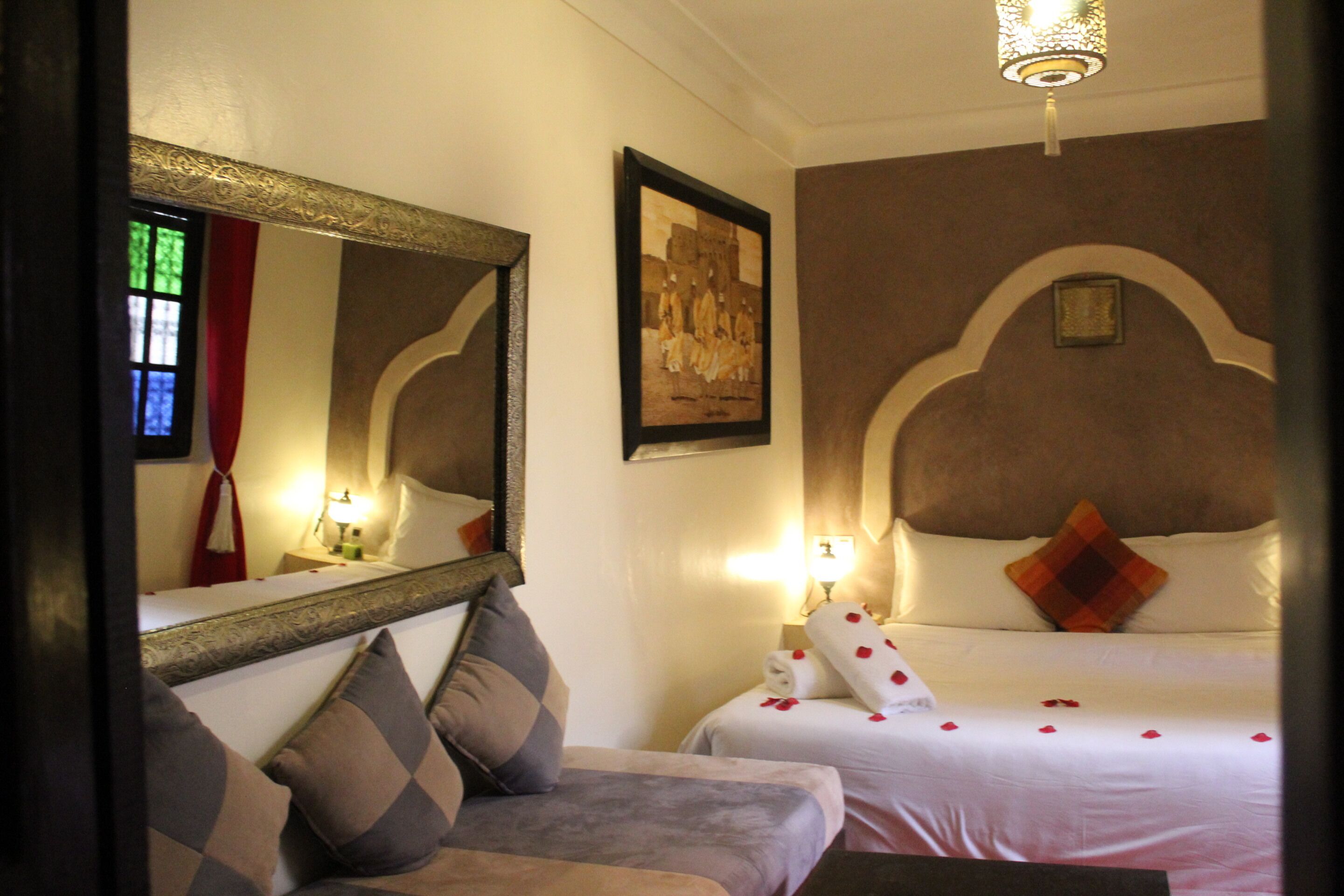 Une chambre d’hôtel avec un lit, un canapé, un miroir et un tableau au mur.