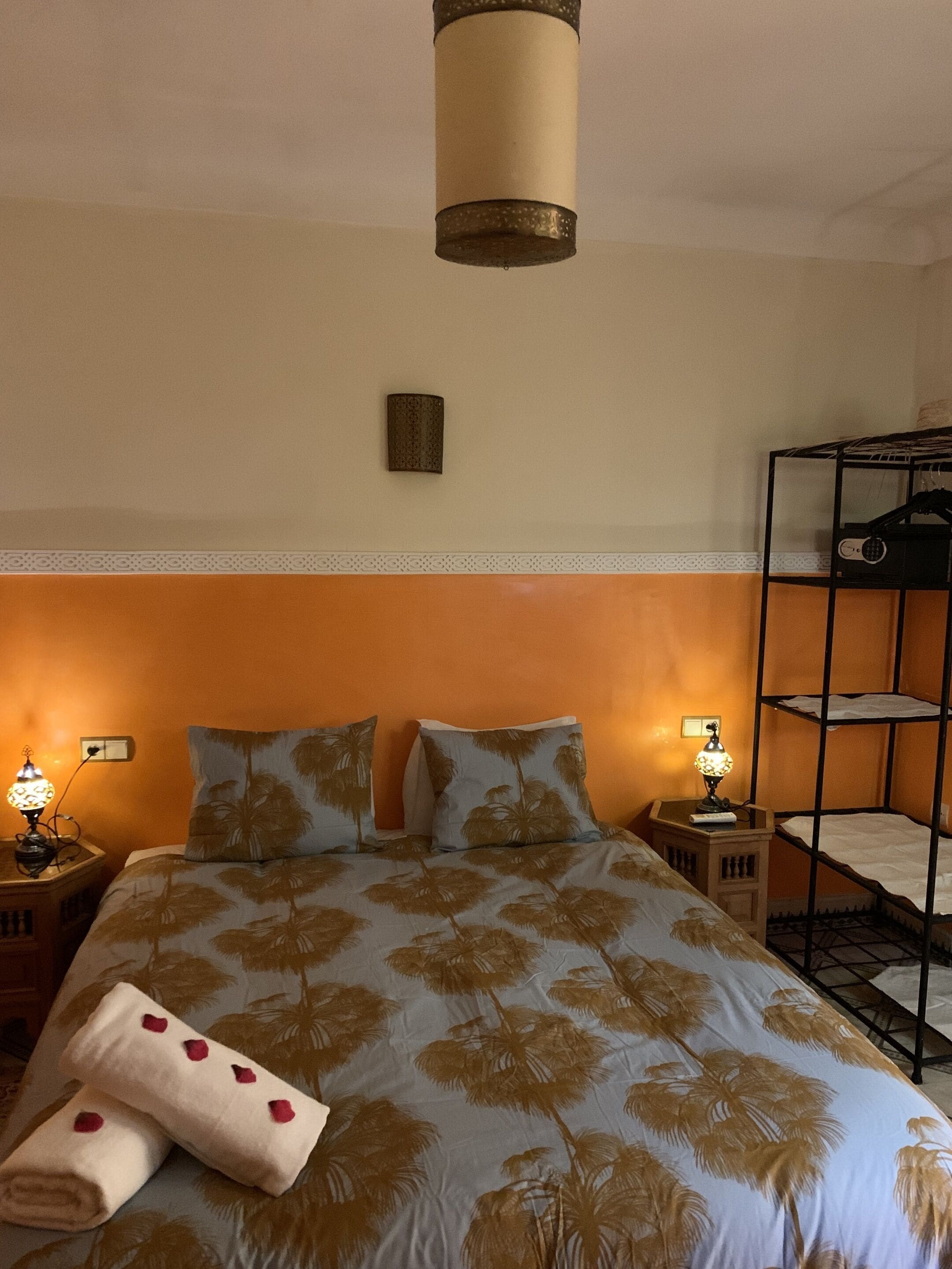 Ein Hotelzimmer mit einem Bett, zwei Nachttischen mit Lampen, einem Schlafstock und einer Wandleuchte.