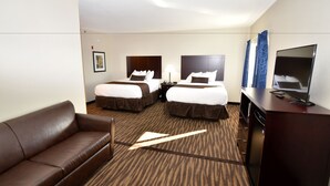 A hotel room with two beds, a sofa, a TV, and a desk. - Cornerstone Inn & Suites (Oelwein)