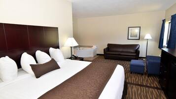 A hotel room with a large bed, a sofa, a desk, a lamp, and a picture on the wall.
