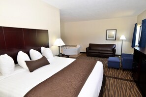 A hotel room with a large bed, a sofa, a desk, a lamp, and a picture on the wall.