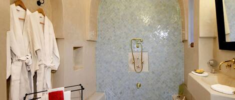 A bathroom with a bathtub, a sink, and a mirror. There are towels and robes hanging on a rack.