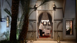 An indoor dining area with a table set for two, a waiter, and decorative lanterns. - Dar Housnia (Marrakech)