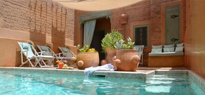 Una piscina al aire libre, sombrillas, sillones reclinables de piscina