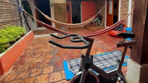An outdoor exercise area with a stationary bike, a hammock, and exercise mats. - Karuss Hostel (Bogotá)