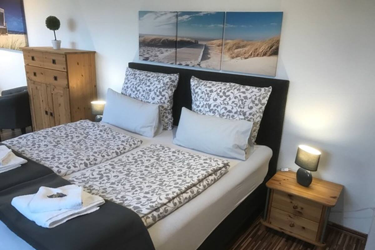 A neatly made bed with patterned bedding, a bedside lamp, and a wooden nightstand.
