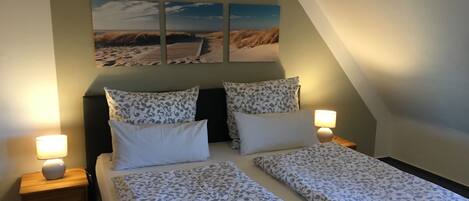 Une chambre à coucher avec un lit, deux tables de chevet, une lampe et un tableau au mur.