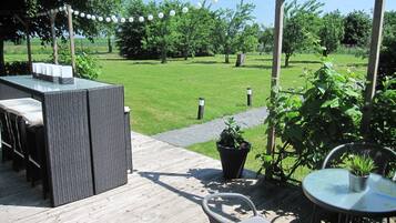 Relax on the patio surrounded by lush greenery and enjoy a meal at the small table.