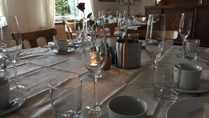 Mesa de comedor dispuesta con copas de vino, platos y una vela.