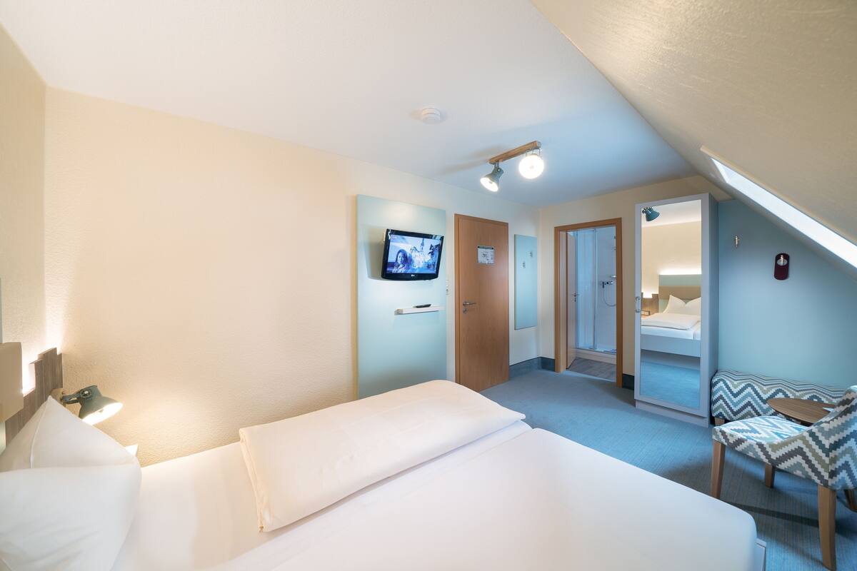 A hotel room with a bed, a TV, a desk, and a chair.