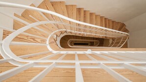 A spiral staircase with wooden steps and white railings. - Appartement 7up (Hamburg)