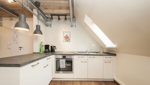 A kitchen with white cabinets, a built-in oven, a sink, and pendant lights. - Appartement 7up (Hamburg)