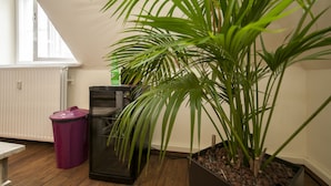 A room with a large potted plant, a trash bin, and a radiator. - Appartement 7up (Hamburg)