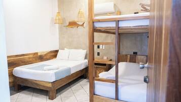 Een kamer met een houten stapelbed, een enkel bed en een klein tafeltje.