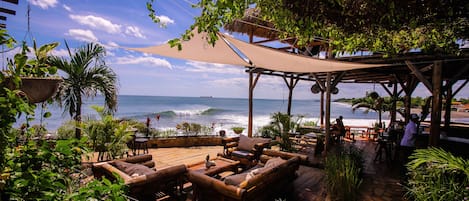 A wooden deck with outdoor seating, overlooking the ocean.