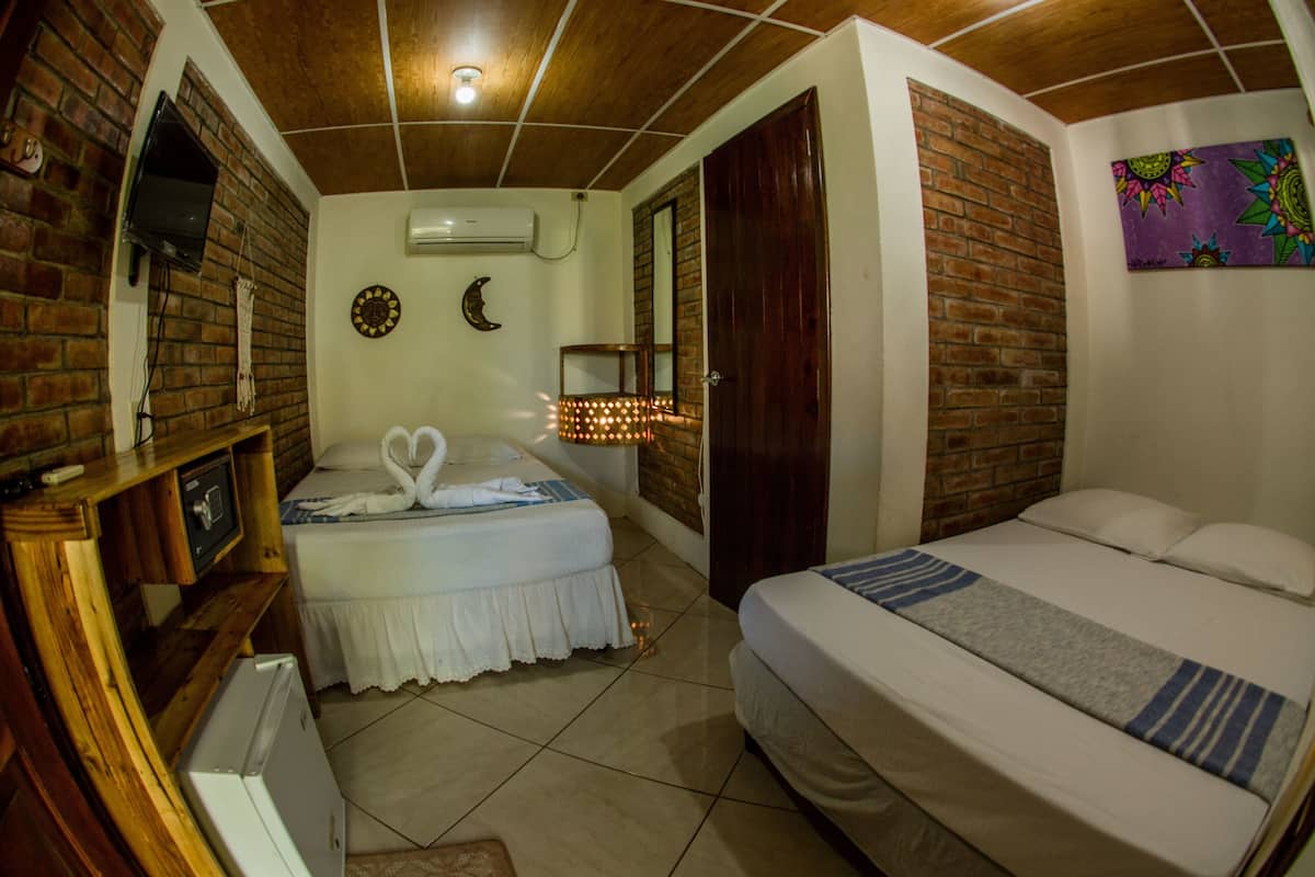 Un dormitorio con dos camas, un televisor, un reloj y aire acondicionado instalado en la pared.