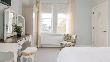 A bedroom with a bed, a dresser with a mirror, a chair, and a window with curtains.