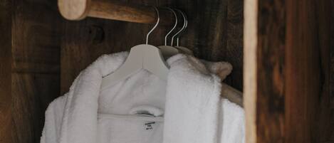 A white robe hanging on a wooden hanger in a wooden room.