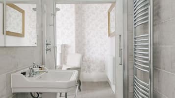 Une salle de bain moderne avec une douche à l’italienne, un lavabo blanc et un sol carrelé.