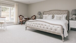 Une chambre à coucher avec un grand lit, deux tables de chevet avec des lampes, une chaise et une fenêtre avec des rideaux.
