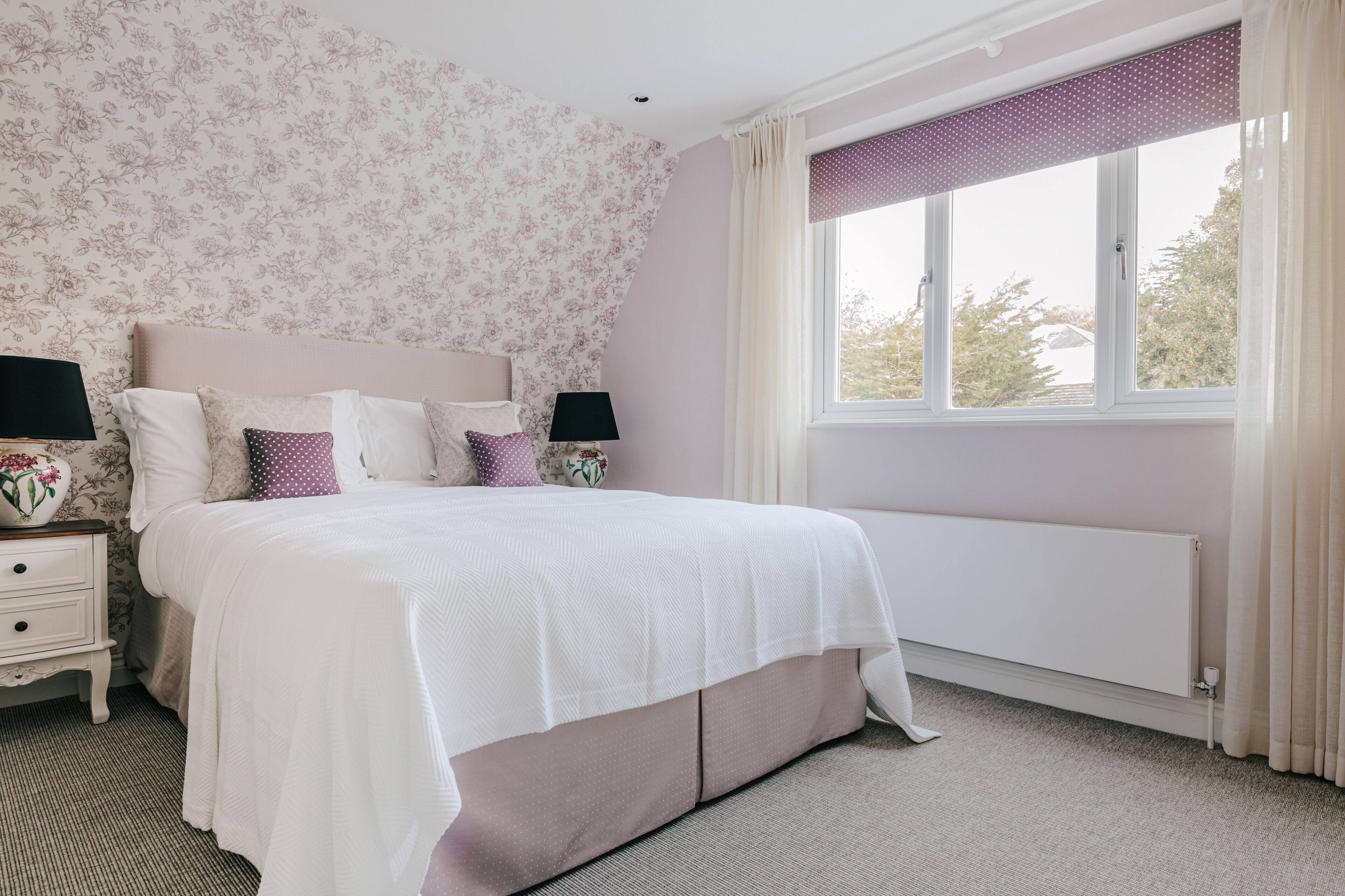 A bedroom with a bed, nightstands, and a window with curtains.