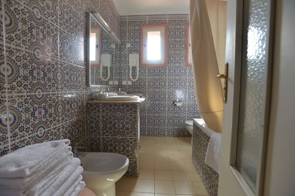 Une salle de bain avec des carreaux décorés, des toilettes, un lavabo et un miroir.