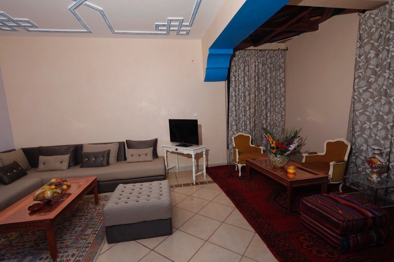 A living room with a sofa, ottoman, coffee table, TV, and a dining area with chairs and a table.