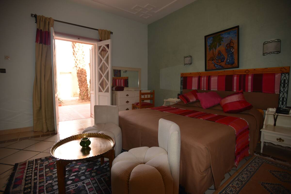 Une chambre à coucher avec un lit, une chaise, une table et un tableau accroché au mur.