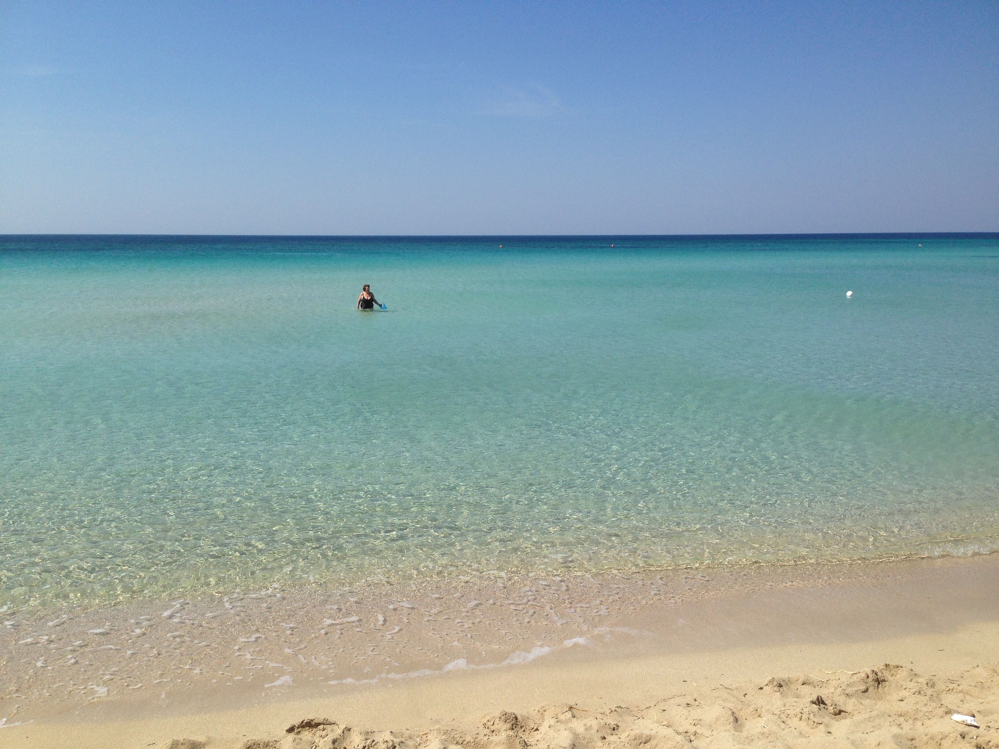 A beach with clear turquoise water and a sandy shore.