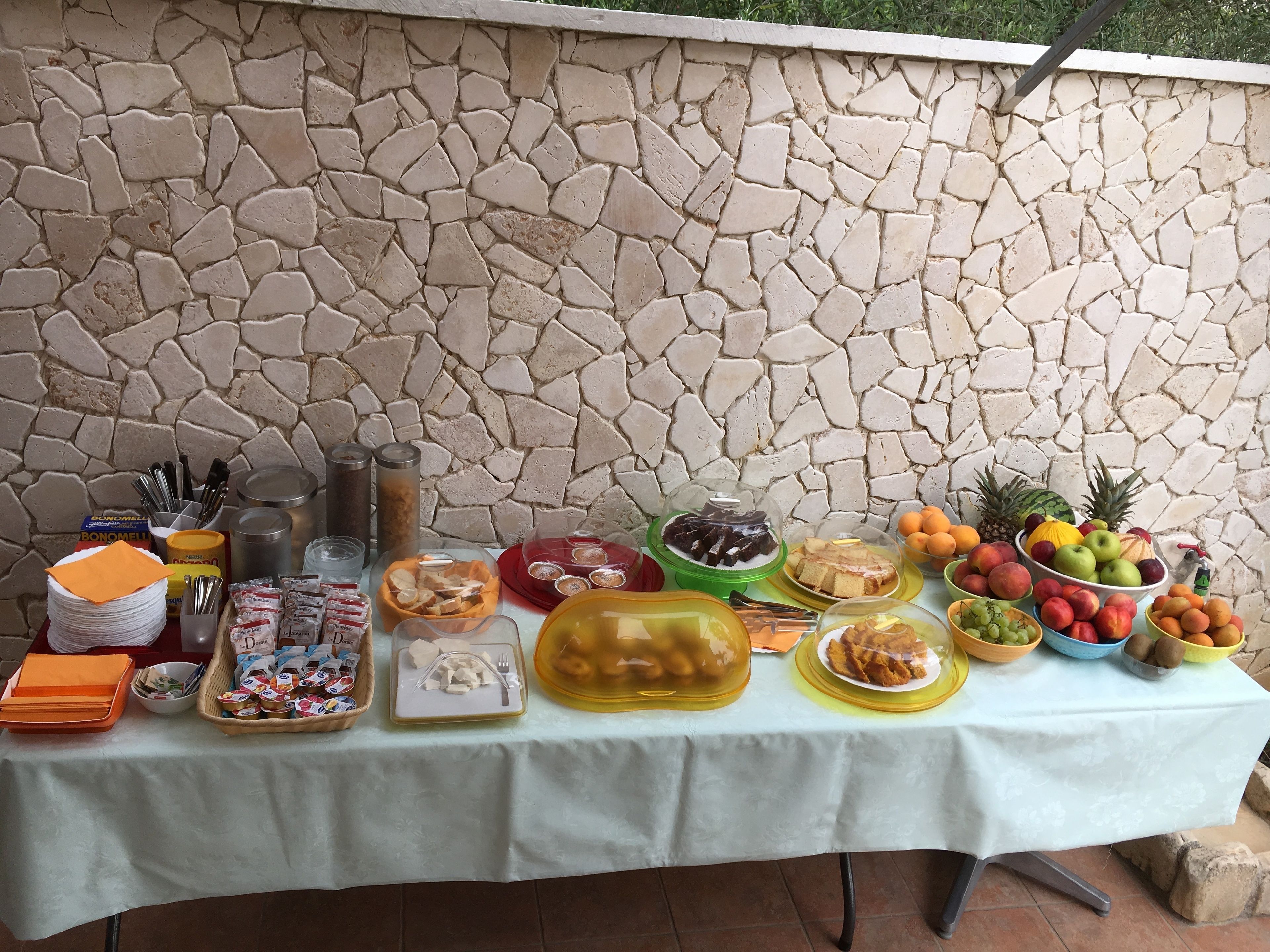 Una mesa dispuesta contra una pared de piedra, con diversos alimentos y condimentos.