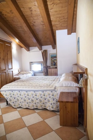 A bedroom with a large bed, wooden beams on the ceiling, and a window with curtains. - Alloggio Casa Hellen (Monteforte d'Alpone)