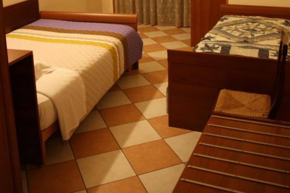 A hotel room with two beds, a television, a desk, and a window with curtains.