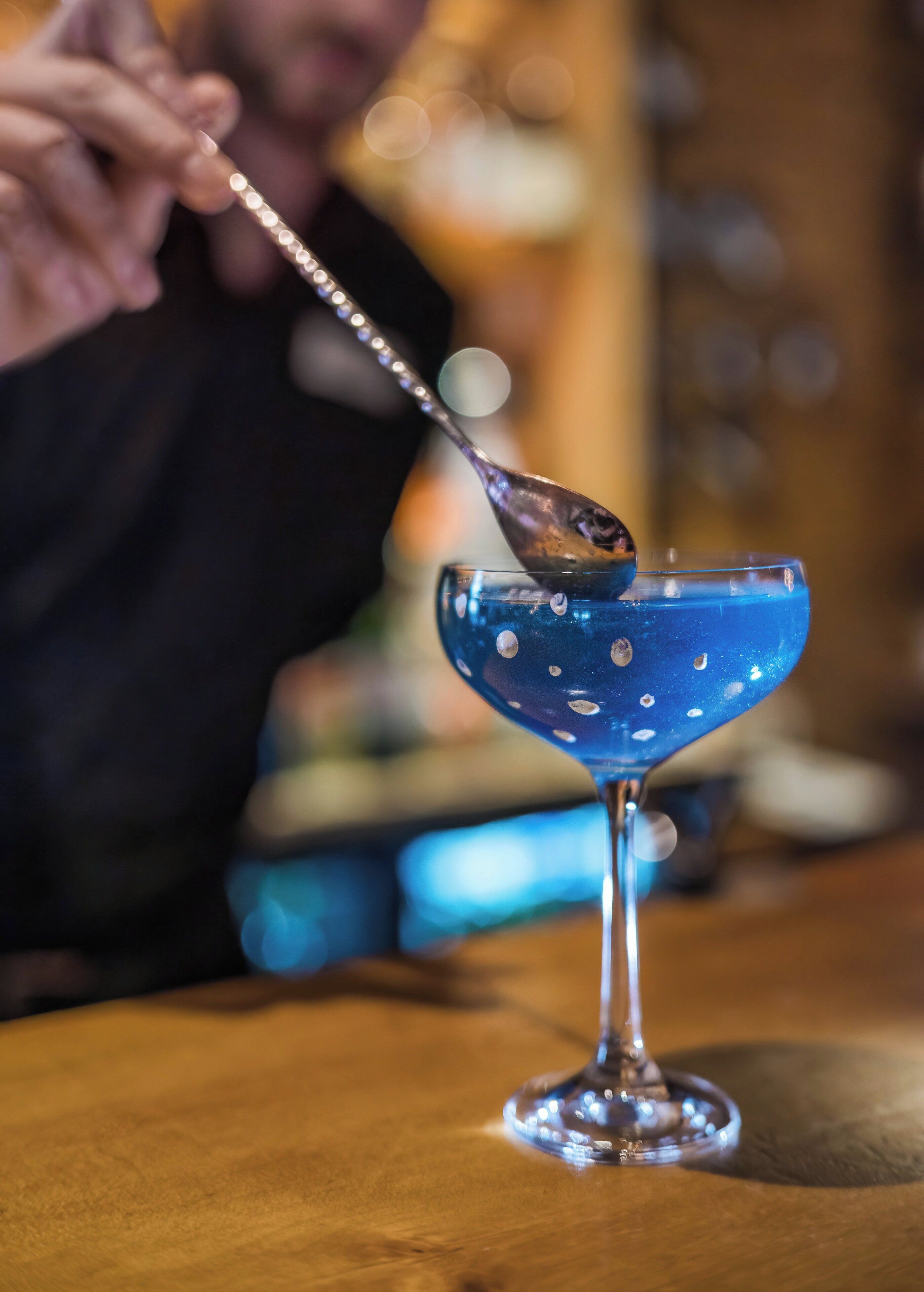 A martini glass with a spoon on a wooden table.