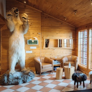 A log cabin interior with a large bear sculpture, leather furniture, and wooden walls. - Hotel Rangá (Rangárþing ytra)
