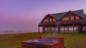 A log cabin with a hot tub on a grassy area, overlooking a body of water. - Hotel Rangá (Rangárþing ytra)