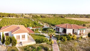 Una villa con techo de tejas, rodeada por un jardín cuidado y un viñedo.
