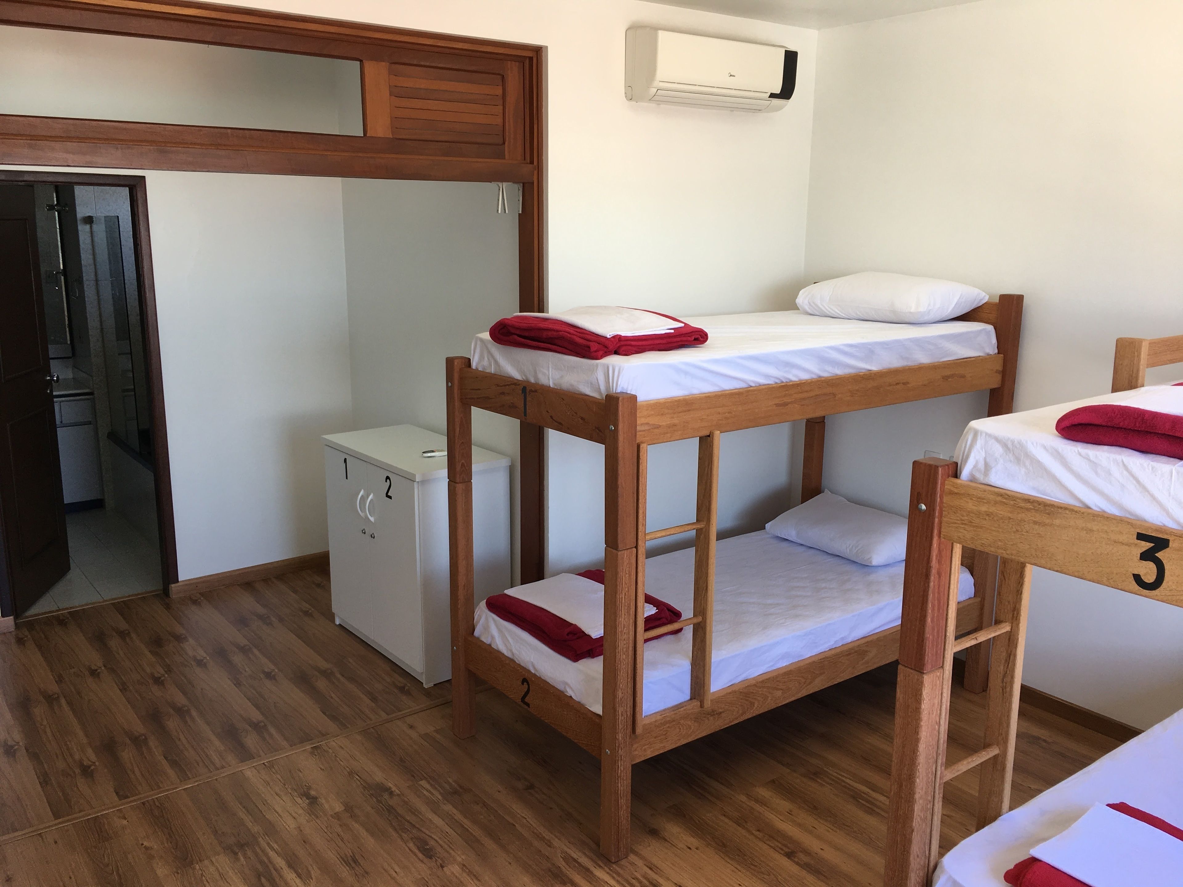 Una habitación con literas, una kitchenette pequeña y un equipo de aire acondicionado.